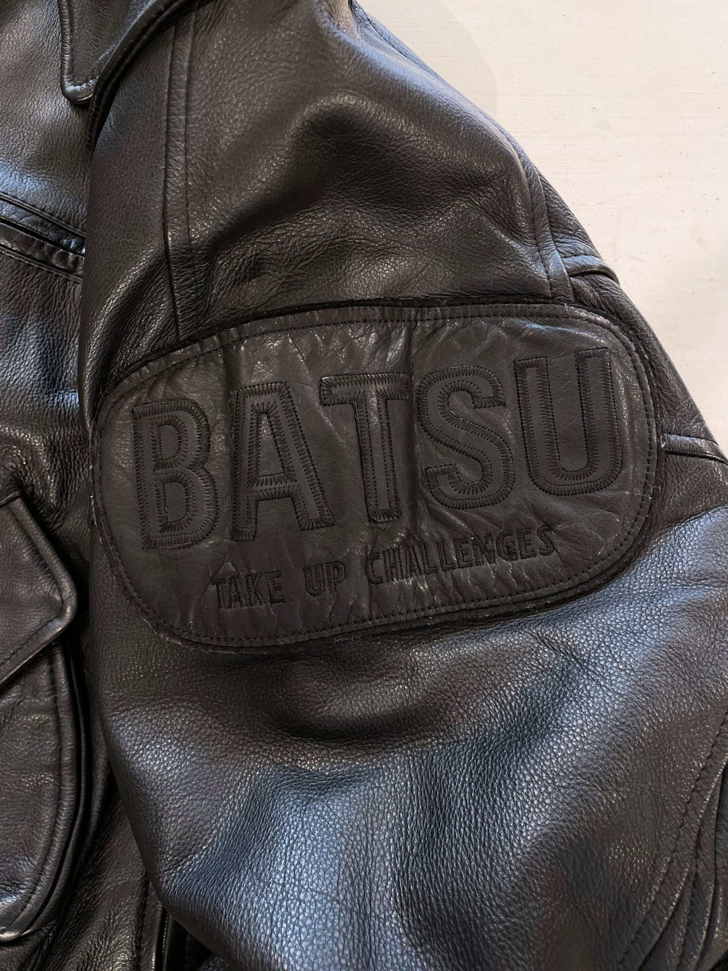 Ba-tsu 1980s thick black leather bomber jacket with shoulder patch